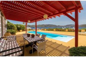 a patio with a table and chairs and a pool at Villa Agios Sostis Mykonos in Mýkonos City
