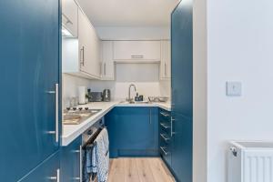a blue kitchen with white cabinets and a sink at Modern 2 Bedroom Apt in City Centre Free Parking with Fast WiFi Near Arena in Nottingham +46 photos
