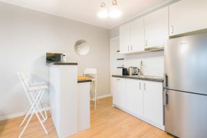 une cuisine avec des armoires blanches et un réfrigérateur dans l'établissement Przestronny Apartament z Tarasem i Parkingiem w Gdyni by Noclegi Renters, à Pogórze