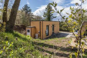 a tiny house in a field with a tree at Tinyhaus Brekendorf Kammberg in Brekendorf