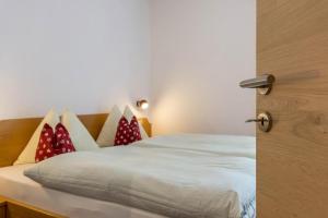 a bedroom with a bed with red and white pillows at Haus Lohengrin Ferienwohnung 2 in Siusi