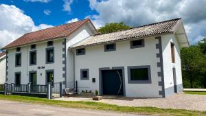 een groot wit gebouw met een grote garage bij Gîte Noël - Jacuzzi, Sauna et Calme absolu in La Celle-sous-Gouzon