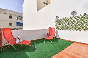 Dos sillas sentadas junto a una pared con césped verde. en Estudio 1 D en el centro de Nerja, en Nerja 15 fotos más