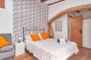 1 dormitorio con cama con almohadas de color naranja y sofá en Estudio 1 D en el centro de Nerja, en Nerja