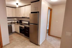 Una cocina con refrigerador y gabinetes de acero inoxidable. en Antina 12 en Santa Pola, en Santa Pola