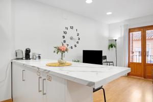 a kitchen with a white counter and a clock on the wall at Ca L'Oliera in Denia +15 photos