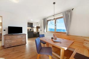 a dining room with a wooden table and a large window at Hauserhof in Lagundo