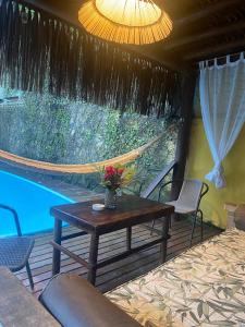 a patio with a table and a hammock next to a pool at Pousada Grafite in Trancoso