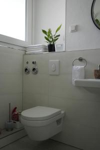 a white bathroom with a toilet and a plant at Modernes 2-Zimmer Apartment mit Balkon in Münster