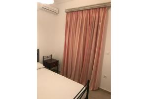 a room with two beds and a pink curtain at Nektarios apartment in Nikiana +5 photos
