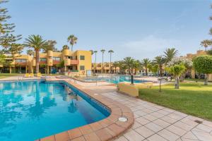 a pool at a resort with palm trees and condos at Casa Del Caballero Corralejo in Corralejo