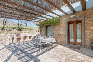 un patio avec une table et des chaises sous une pergola dans l'établissement Podere in Volpaia, à Radda in Chianti