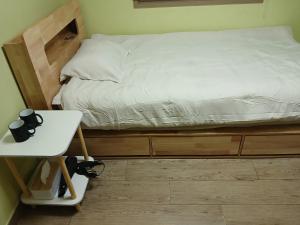 una cama en una habitación con un escritorio y una cama con sábanas blancas en 전북대근처 시외버스터미널 원룸3, en Haga-ri 2 fotos más