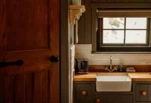 a kitchen with a sink and a window at Shepherds Huts at Ballyness Farm in Dungiven +34 photos
