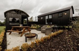 a black tiny house with a patio and a table at Shepherds Huts at Ballyness Farm in Dungiven