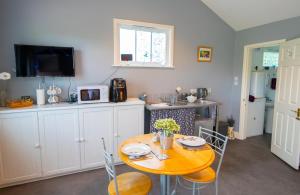 a kitchen with a table with chairs and a microwave at The Den - Winchelsea in Winchelsea +11 photos