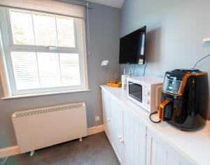 a room with a microwave and a television on a counter at The Den - Winchelsea in Winchelsea