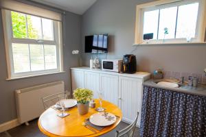 a dining room with a table and a kitchen at The Den - Winchelsea in Winchelsea