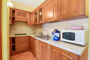 a kitchen with wooden cabinets and a white microwave at Residence Appartamento Roma in Civate