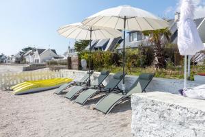 a group of chairs and umbrellas on the beach at Villa vue mer les pieds dans l'eau in Loctudy