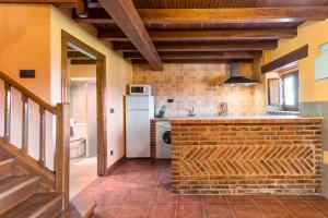 eine Küche mit einer Backsteintheke und einem Kühlschrank in der Unterkunft Casa Alba in Bárcena de Cicero