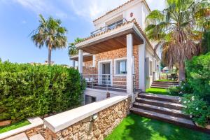 a house with a stone wall and palm trees at Bahamas 2 in Son Serra de Marina