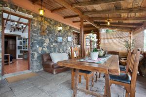 a dining room with a wooden table and a stone wall at Finca el pilar in La Guancha