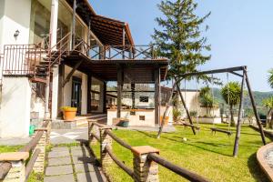 a house with a wooden deck and a yard at Villa immersa nel verde dell Etna in Piedimonte Etneo