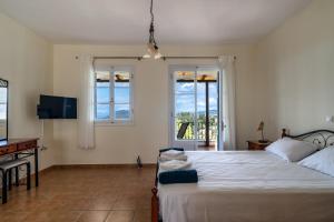 een slaapkamer met een bed, een televisie en ramen bij Afroksilia Villa Krinos in Katouna