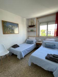 a bedroom with two beds and a chair and a window at Apartamento en primera línea de mar in Roda de Bará