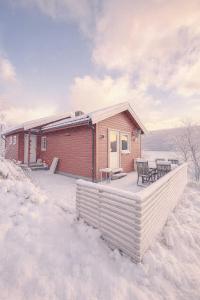 トロムソにあるNordic Retreatの雪の中にデッキがある小さな家