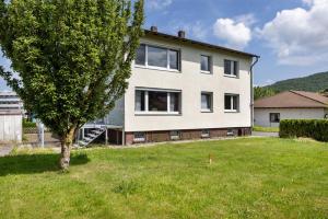 a large white house with a tree in the yard at Haus Lerchenweg B in Bad Wildungen