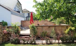 a garden with a brick retaining wall and a red umbrella at Ferienwohnung Honacker in Steißlingen +2 photos
