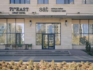 Un edificio con mesas y sillas delante. en 71 East Apart Hotel, en Astana