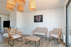sala de estar con 3 sillas y TV en Villa Léa Vue mer d'exception Plage, en Batz-sur-Mer