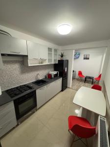 a kitchen with white cabinets and red chairs and a table at AA home in Craiova International Airport