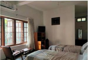Un dormitorio con una cama, una silla y una ventana en Anashwara, en Kozhikode 41 fotos más