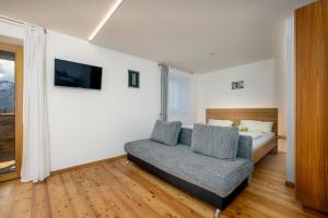 una camera da letto con un letto, un divano e una TV di Oberköbenhof Wohnung Tal a Laces