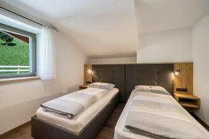 Dos camas en una habitación con ventana. en Sunnseitn Lodge Apt Mountainsuite, en Stulles