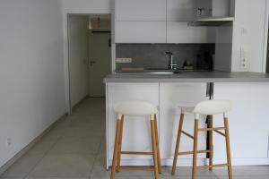 a kitchen with two white bar stools and a sink at Modernes 2-Zimmer Apartment mit Balkon in Münster +6 photos