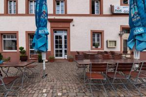 a group of tables and chairs with umbrellas in front of a building at Restaurant Fewo Golsong in Thaleischweiler-Fröschen