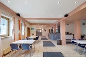 a dining room with tables and chairs and a kitchen at Hotel Neue Krone - Markt Erlbach in Markt Erlbach