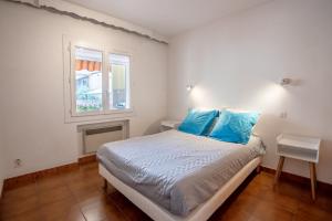Un dormitorio con una cama con almohadas azules y una ventana. en Location La Londe, en La Londe-les-Maures