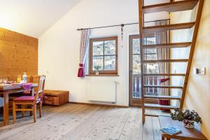 a living room with a table and a spiral staircase at Lechnerhof Apt 4 in Braies
