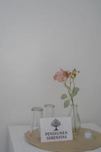 a table with a plate with a vase with a flower at Pensiunea Serenitas in Sebeşel