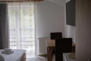 a room with a table and a large window with a desk and a tableablish at Pensiunea Serenitas in Sebeşel