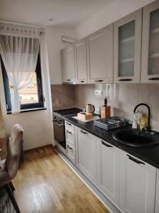 Una cocina con gabinetes blancos y un fregadero y una ventana. en Apartman Havjar Zlatibor, en Zlatibor