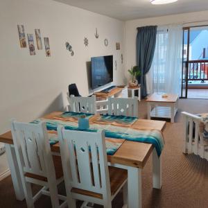 een eetkamer met een tafel, stoelen en een televisie bij Dunes Alcove Mossel Bay Comfortable self catering accommodation just 900 meters from the beach and close to restaurants shops and local attractions in Vosburg