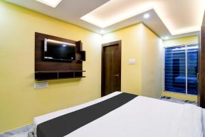 a bedroom with a bed and a tv on the wall at Hotel O The Crown in Kolkata +22 photos
