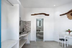 a bathroom with white walls and a sink and a mirror at Politimis Studio N1 in Amorgos